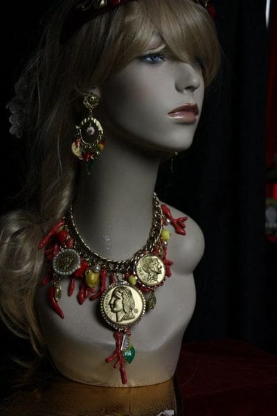 A mannequin wearing jewelry and earrings with red coral.