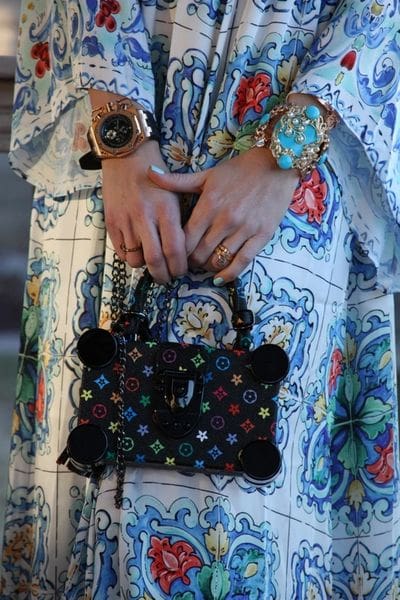 A woman holding onto a purse with colorful buttons.