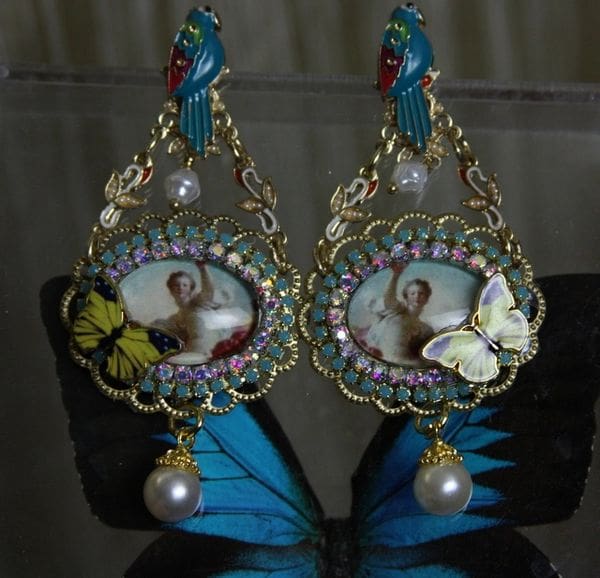 A pair of earrings with pictures and pearls on them.