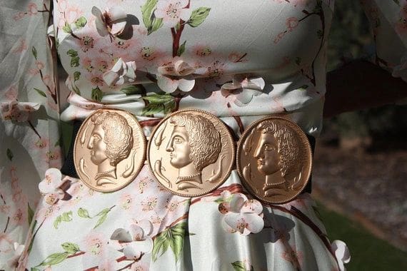 Three gold coins are on a belt.