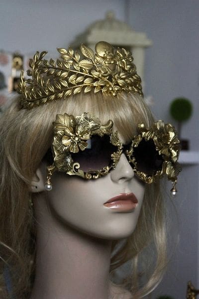 A mannequin wearing gold sunglasses and a crown.