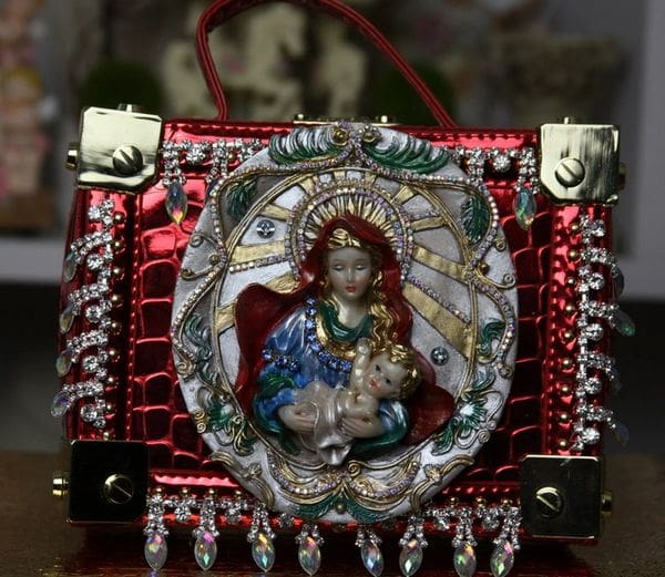 A red purse with a picture of jesus and the virgin mary.