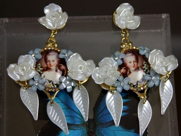 A pair of earrings with pearls and a picture.