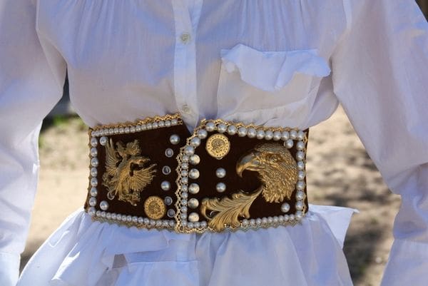 A woman wearing a white shirt and brown belt.