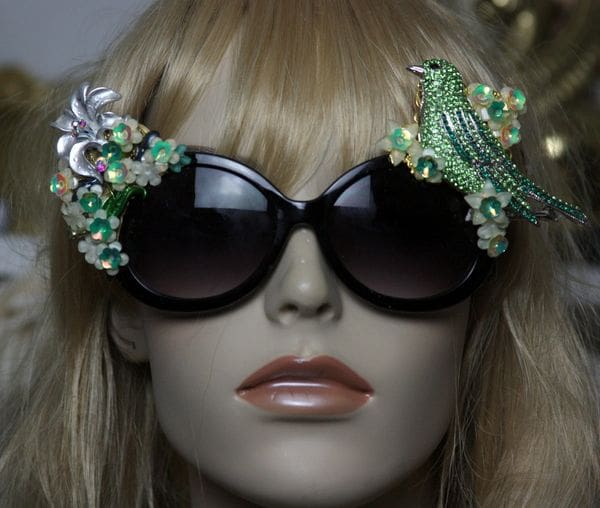 A mannequin wearing sunglasses with green flowers on them.