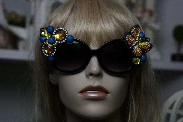 A mannequin wearing sunglasses with yellow and blue butterflies.
