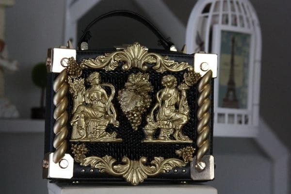 A black and gold purse with two figures on it.
