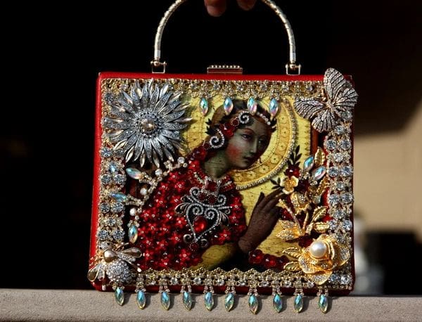 A woman holding onto a red purse with jewels