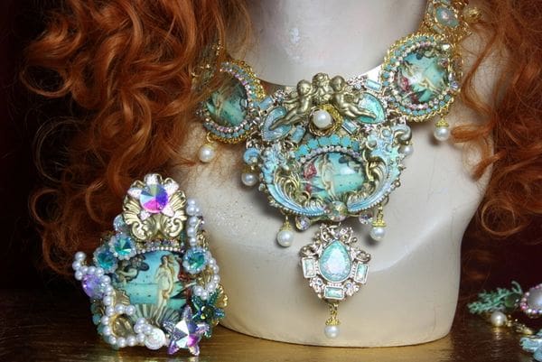 A woman with red hair wearing a necklace and ring.