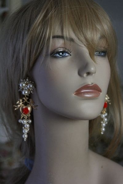 A mannequin wearing earrings with red stones.