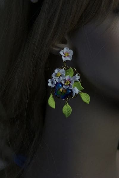 A woman wearing earrings with flowers and leaves.