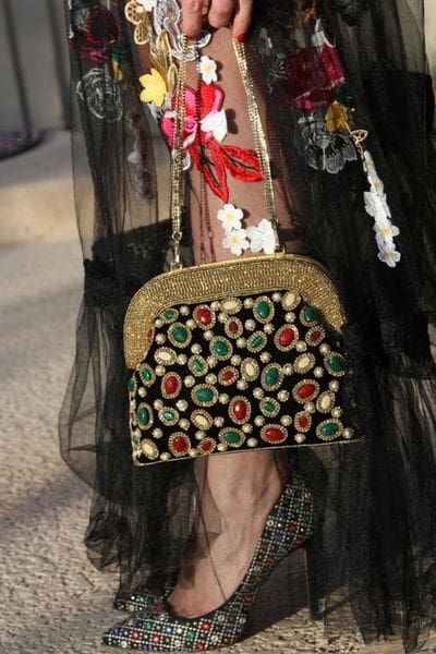 A woman wearing a black dress and holding onto a purse