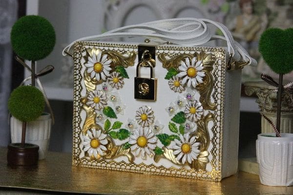 A white purse with gold and green flowers.