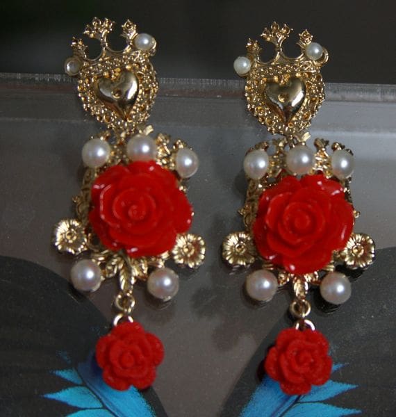 A pair of earrings with red roses and blue feathers.