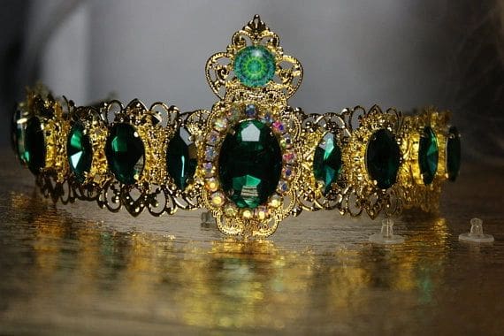 A close up of a crown with green stones