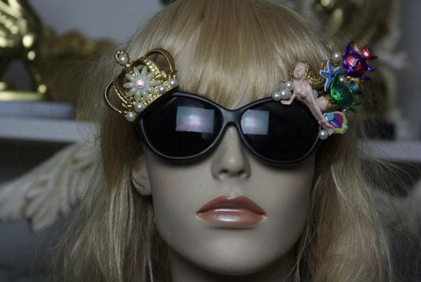 A mannequin wearing sunglasses and a crown.