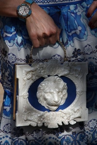 A woman holding onto a bag with a lion head on it