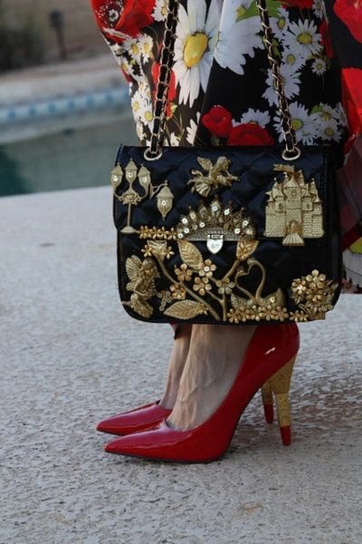 A woman in red high heels holding onto her purse