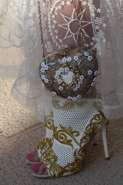 A woman wearing a dress and holding onto a purse