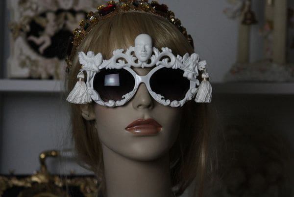 A mannequin wearing white sunglasses with ornate design.