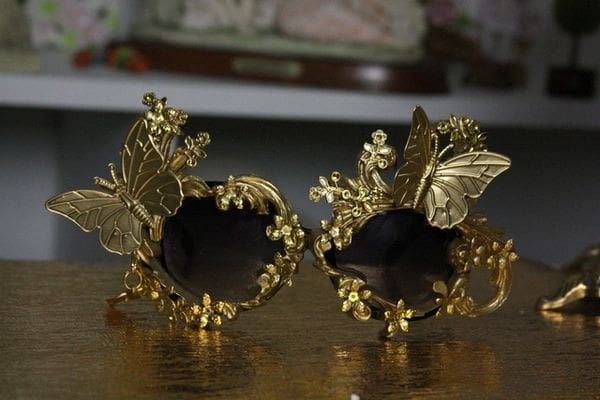 A pair of gold butterfly ornaments sitting on top of a table.