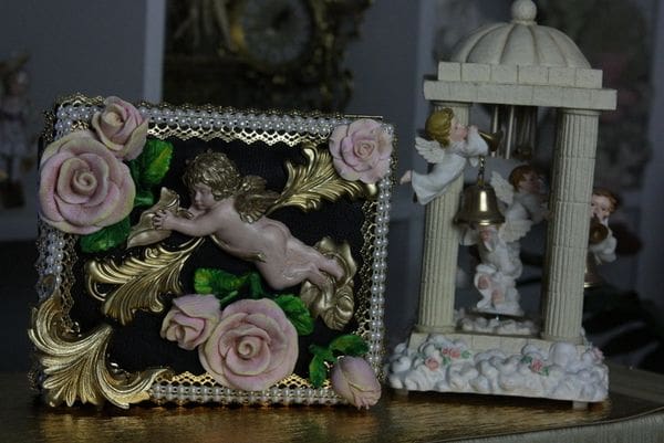 A picture frame with a cherub and roses on it.