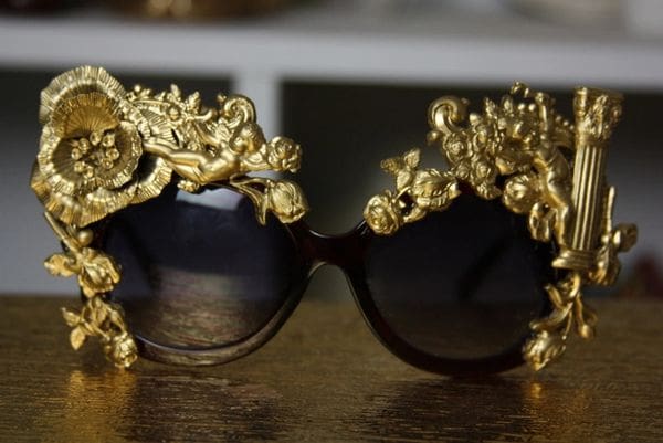 A pair of sunglasses with gold frames and dragon heads on them.