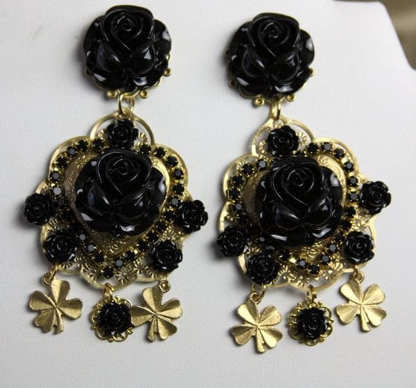 A pair of black and gold earrings on top of a white surface.