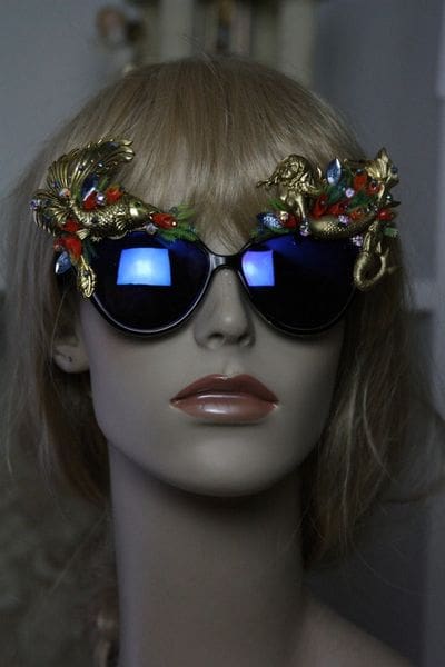 A mannequin wearing sunglasses with gold dragon 's on them.