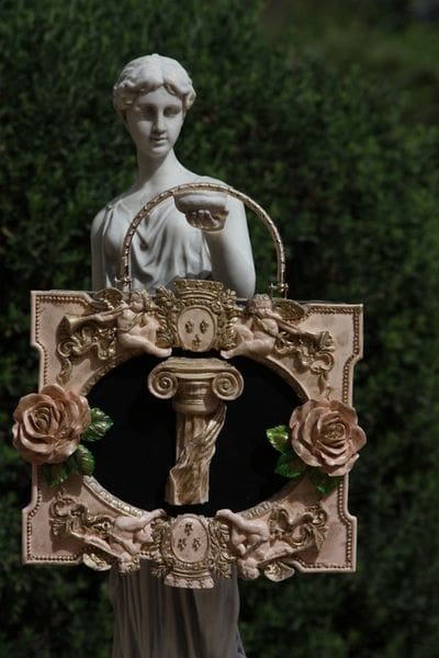A statue of a woman in front of a picture frame.