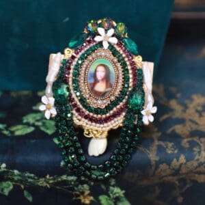 A green and white necklace with a picture of jesus.