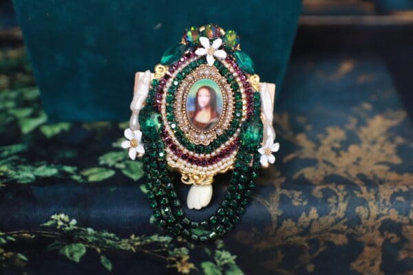A green and white necklace with a picture of jesus.