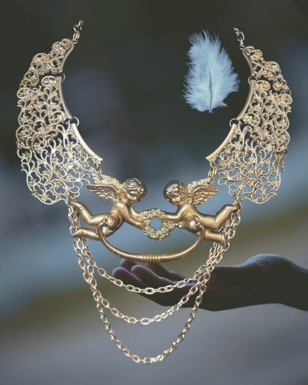 A necklace with two angels on it and feathers
