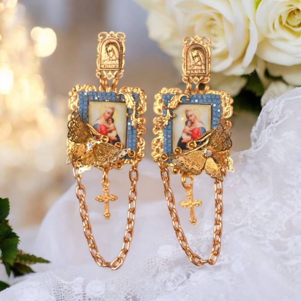 A pair of earrings with gold chains and a picture.