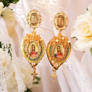 A pair of earrings with jesus and mary on them.