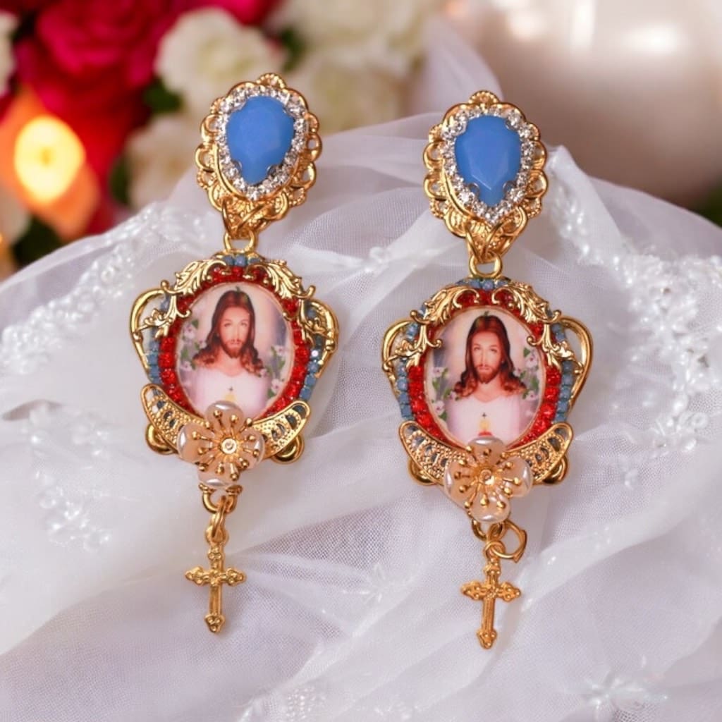 A pair of earrings with jesus and cross on them.