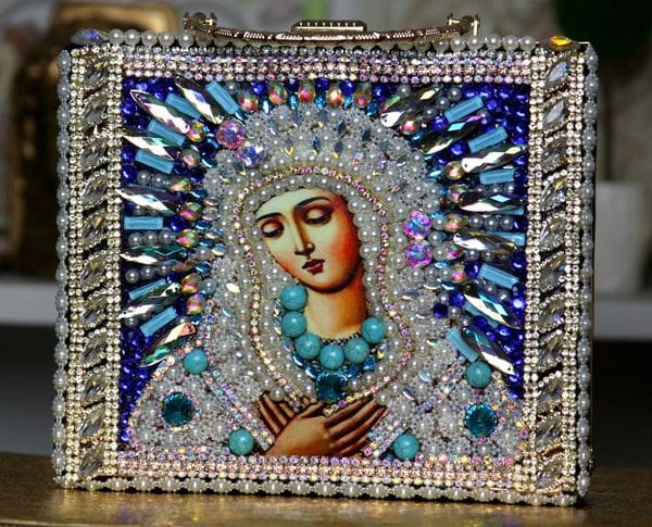 A painting of the virgin mary with blue beads and crystals.