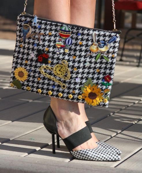 A woman 's legs and purse with flowers on it.