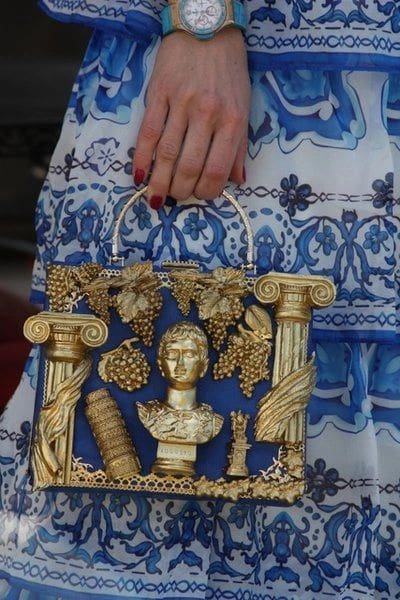 A woman holding onto a blue and gold bag