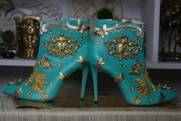 A pair of turquoise shoes with gold designs on them.