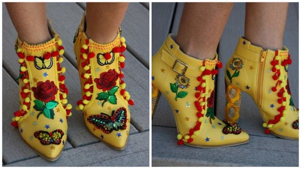 A pair of yellow boots with butterflies and flowers on them.