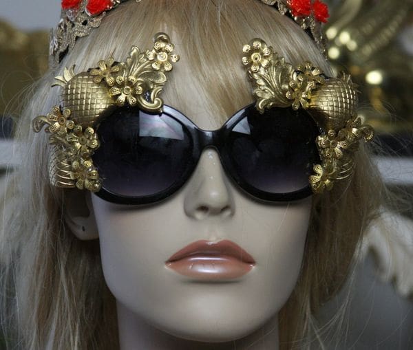 A mannequin wearing sunglasses with gold frames and red flowers.