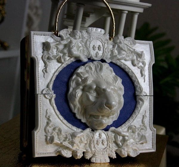 A white and blue plaque with a lion 's head on it.