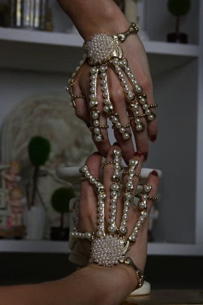 A woman 's hands with pearls and gold chains